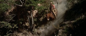 Movie still from “Big Jake” (1971), directed by George Sherman – A man riding on the back of a brown horse; Wide shot, Low angle