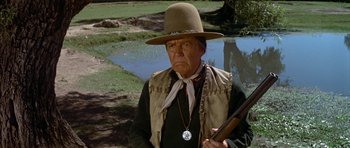 Movie still from “Big Jake” (1971), directed by George Sherman – An older man in a cowboy hat holding a rifle; Close Up shot, Over the shoulder angle