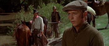 Movie still from “Big Jake” (1971), directed by George Sherman – A group of men walking down a dirt road; Close Up shot, Over the shoulder angle