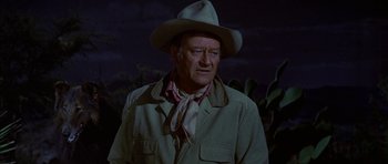 Movie still from “Big Jake” (1971), directed by George Sherman – A man in a cowboy hat standing in front of a field; Medium shot, Over the shoulder angle