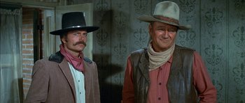 Movie still from “Big Jake” (1971), directed by George Sherman – Two men in cowboy hats standing next to each other; Medium shot, Low angle