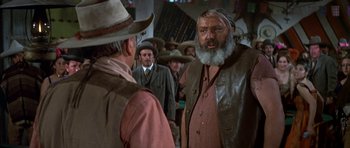 Movie still from “Big Jake” (1971), directed by George Sherman – A group of men standing next to each other in a room; Medium shot, Over the shoulder angle