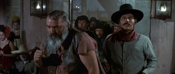 Movie still from “Big Jake” (1971), directed by George Sherman – A group of men standing next to each other in a room; Medium shot, Low angle