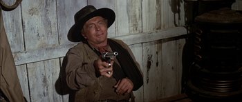 Movie still from “Big Jake” (1971), directed by George Sherman – A man holding a gun while wearing a hat; Close Up shot, Over the shoulder angle