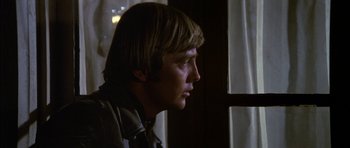 Movie still from “Big Jake” (1971), directed by George Sherman – A young man looking out of a window at night; Close Up shot, Over the shoulder angle