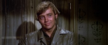 Movie still from “Big Jake” (1971), directed by George Sherman – A man with blonde hair and a brown leather jacket; Close Up shot, Over the shoulder angle