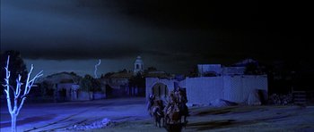 Movie still from “Big Jake” (1971), directed by George Sherman – A group of people riding horses on a dirt road; Extreme Wide shot, Low angle