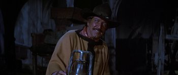 Movie still from “Big Jake” (1971), directed by George Sherman – A man in a cowboy hat holding a lantern; Medium shot, Low angle
