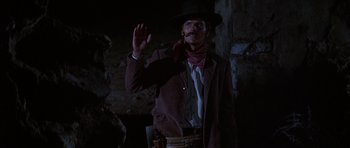 Movie still from “Big Jake” (1971), directed by George Sherman – A man wearing a cowboy hat and holding his hand up; Medium shot, Low angle