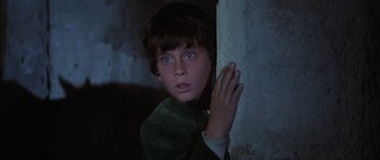 Movie still from “Big Jake” (1971), directed by George Sherman – A young boy is leaning against a wall; Close Up shot, Low angle