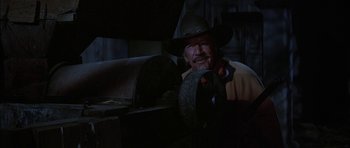 Movie still from “Big Jake” (1971), directed by George Sherman – A man wearing a cowboy hat is smiling for the camera; Medium shot, Low angle