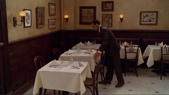 Movie still from “Big Night” (1996), directed by Stanley Tucci – A man in a suit setting a table in a restaurant; Wide shot, High angle