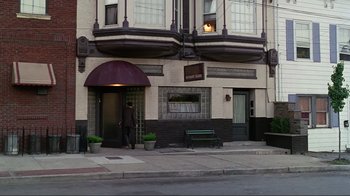 Movie still from “Big Night” (1996), directed by Stanley Tucci – A man standing outside of a building on the sidewalk; Extreme Wide shot, High angle