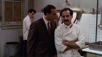 Movie still from “Big Night” (1996), directed by Stanley Tucci – A man in a suit standing next to a man in a chef's outfit; Medium shot, Over the shoulder angle