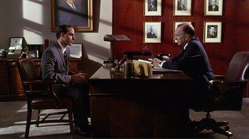 Movie still from “Big Night” (1996), directed by Stanley Tucci – Two men sitting at a desk in front of each other; Wide shot, High angle