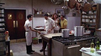 Movie still from “Big Night” (1996), directed by Stanley Tucci – A group of people standing in a kitchen preparing food; Wide shot, High angle