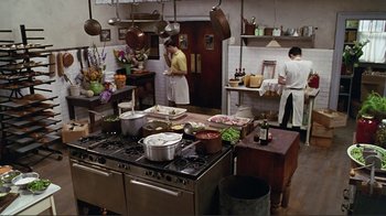 Two men in a kitchen preparing food on a stove top