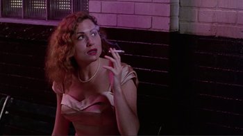 Movie still from “Big Night” (1996), directed by Stanley Tucci – A woman smoking a cigarette while sitting on a bench; Medium shot, Low angle