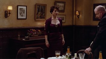 Movie still from “Big Night” (1996), directed by Stanley Tucci – A woman standing in front of a dining room table; Medium shot, Over the shoulder angle