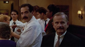 Movie still from “Big Night” (1996), directed by Stanley Tucci – A group of men in suits and ties sitting next to each other; Medium shot, Over the shoulder angle