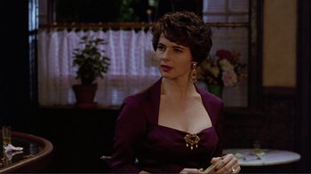 Movie still from “Big Night” (1996), directed by Stanley Tucci – A woman wearing a purple dress and a gold necklace; Close Up shot, Over the shoulder angle