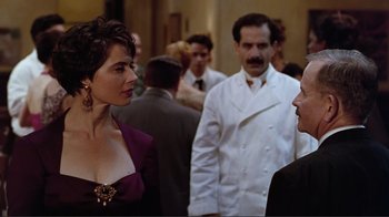 Movie still from “Big Night” (1996), directed by Stanley Tucci – A woman in a purple dress talking to a man in a white suit; Medium shot, Over the shoulder angle
