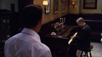 Movie still from “Big Night” (1996), directed by Stanley Tucci – A man playing the piano while another man looks on; Wide shot, Over the shoulder angle