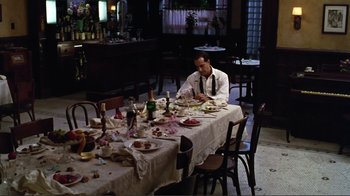 Movie still from “Big Night” (1996), directed by Stanley Tucci – A man sitting at a table with a plate of food on top of it; Wide shot, High angle