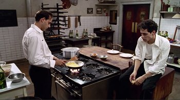 Movie still from “Big Night” (1996), directed by Stanley Tucci – A man and a woman cooking food on a stove; Medium shot, High angle