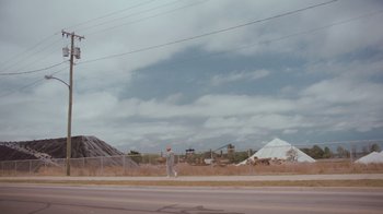 Movie still from “Swan Song” (2021), directed by Benjamin Cleary – A man walking down a street near a construction site; Extreme Wide shot, Low angle