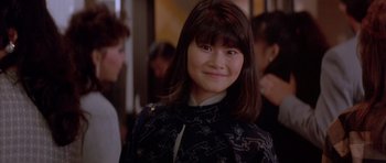 Movie still from “Big Trouble in Little China” (1986), directed by John Carpenter – A young woman with long brown hair wearing a dress; Close Up shot, Over the shoulder angle