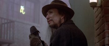 Movie still from “Big Trouble in Little China” (1986), directed by John Carpenter – A man in a hat and a brown jacket; Close Up shot, Over the shoulder angle