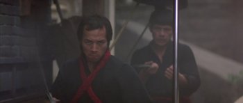 Movie still from “Big Trouble in Little China” (1986), directed by John Carpenter – A man in a black shirt and a man in a black shirt; Medium shot, Low angle