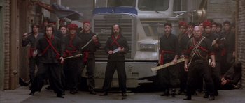 Movie still from “Big Trouble in Little China” (1986), directed by John Carpenter – A group of men standing in front of a large truck; Wide shot, Low angle