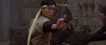 Movie still from “Big Trouble in Little China” (1986), directed by John Carpenter – A young man in a headband is holding his hands out; Medium shot, Low angle