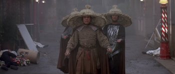 Movie still from “Big Trouble in Little China” (1986), directed by John Carpenter – A group of people in costume walking on a street; Medium shot, Low angle
