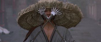 Movie still from “Big Trouble in Little China” (1986), directed by John Carpenter – A person with a straw umbrella on their head; Close Up shot, Low angle