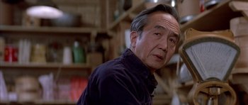 Movie still from “Big Trouble in Little China” (1986), directed by John Carpenter – An older asian man in a dark room; Close Up shot, Low angle
