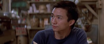 Movie still from “Big Trouble in Little China” (1986), directed by John Carpenter – A person sitting in front of a window; Close Up shot, Low angle