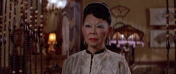 Movie still from “Big Trouble in Little China” (1986), directed by John Carpenter – An older asian woman wearing a white dress; Close Up shot, Low angle