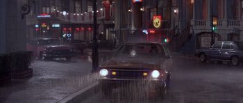 Movie still from “Big Trouble in Little China” (1986), directed by John Carpenter – A car driving down a street at night; Wide shot, High angle
