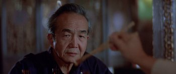 Movie still from “Big Trouble in Little China” (1986), directed by John Carpenter – An older man sitting in front of a mirror; Close Up shot, Over the shoulder angle