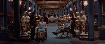 Movie still from “Big Trouble in Little China” (1986), directed by John Carpenter – A group of people standing around in wheelchairs in a room; Wide shot, High angle