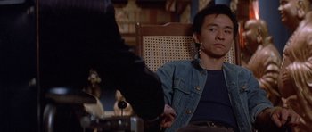 Movie still from “Big Trouble in Little China” (1986), directed by John Carpenter – A man sitting in a chair in front of another man; Medium shot, High angle