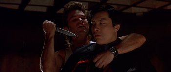 Movie still from “Big Trouble in Little China” (1986), directed by John Carpenter – A man is cutting another man's tie with a knife; Close Up shot, Low angle