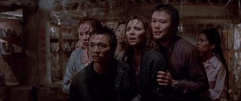 Movie still from “Big Trouble in Little China” (1986), directed by John Carpenter – A group of people standing around each other; Medium shot, High angle