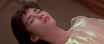Movie still from “Big Trouble in Little China” (1986), directed by John Carpenter – A young woman with her eyes closed is lying on a bed; Close Up shot, High angle