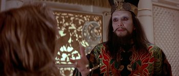 Movie still from “Big Trouble in Little China” (1986), directed by John Carpenter – A man with a beard wearing a crown and a black robe; Close Up shot, Over the shoulder angle