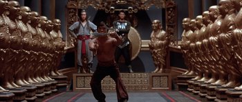Movie still from “Big Trouble in Little China” (1986), directed by John Carpenter – A man holding a sword in front of statues; Wide shot, Low angle