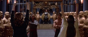 Movie still from “Big Trouble in Little China” (1986), directed by John Carpenter – A group of people standing in front of a statue of a man; Wide shot, Low angle